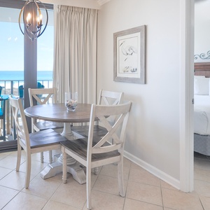 This charming dining area features a round table with four chairs, offering a view of the beachfront from the balcony