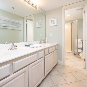 Master bathroom featuring dual sinks, a walk-in shower, and beach-themed artwork for a refreshing vacation experience