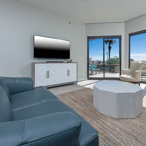 Cozy living area features a blue sofa with queen sleeper, modern coffee table, and large windows to the outdoor patio