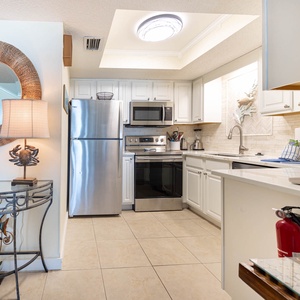 This modern kitchen features stainless appliances, a stylish backsplash, and a cozy dining area with beach-themed decor