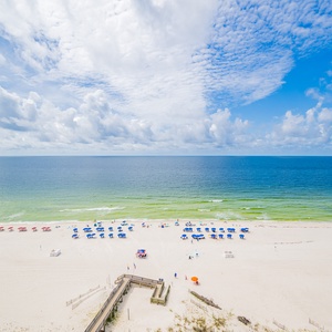 Savor the view of the beach lined with colorful umbrellas and gentle waves lapping at the shore