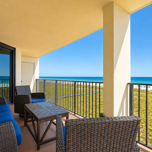 Cozy balcony features blue cushioned seating and a wooden table, offering a perfect spot to relax and enjoy the beach view