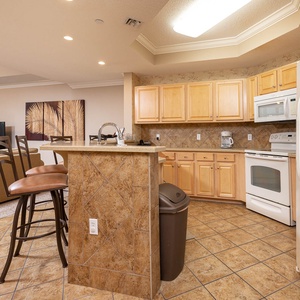 Prepare meals in this kitchen with elegant cabinetry, white appliances, and spacious countertops