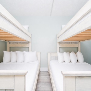 This cozy bedroom features two stylish bunk beds with plush white bedding, perfect for family stays