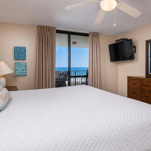 The master suite bedroom features a king bed, flat-screen TV, and a balcony with a view of the tranquil beach