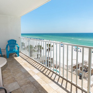 This balcony features vibrant blue chairs and a table, offering a stunning beachfront view perfect for relaxation