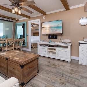 Bright living area featuring a cozy sofa with queen sleeper, rustic coffee table, and a view of the beachfront balcony