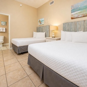 Guest bedroom featuring two double beds with rustic wood headboards and a cozy bedside lamp