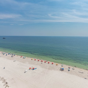 This stunning beachfront view showcases vibrant umbrellas on the white sand and the state park pier in the distance