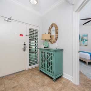 Welcoming entryway featuring coastal decor, a stylish console, and a view of the guest suite with two queens