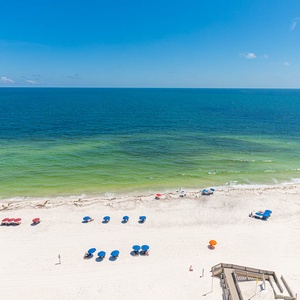Enjoy the beach with colorful umbrellas and gentle waves, taking in the vibrant colors of the gulf waters