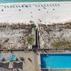 Enjoy the inviting pool area with lounge chairs, leading directly to the beach and vibrant umbrellas for your relaxation