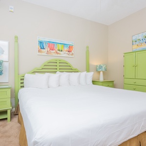 Spacious suite-style bedroom, featuring a large king bed with plush bedding, adjoining bath, and vibrant artwork