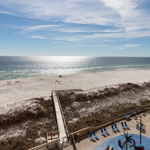 The view showcases a serene beach with glistening water and a sandy shore, framed by the splash park and pool area
