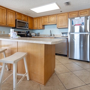 Prepare meals in the bright kitchen, featuring wood cabinets, stainless appliances, and a convenient breakfast bar