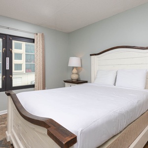 This inviting bedroom features a cozy bed, stylish lamps, and large windows for natural light