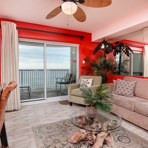 This vibrant living area features a cozy sofa, a large TV, and a stunning beachfront view from the sliding glass doors