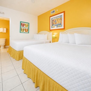 Unwind in this cheerful guest room with two queen beds, vibrant yellow walls, and playful artwork that enhances your stay