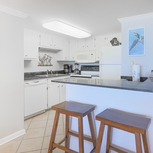 This modern kitchen features sleek countertops, white cabinetry, and bar seating, perfect for casual meals and gatherings