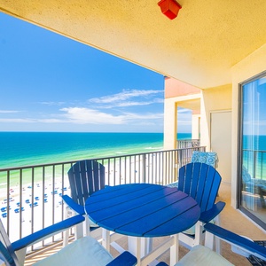 he balcony features comfortable seating with a stunning view of the beach and tranquil blue waters stretching to the horizon