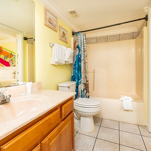 Bright bathroom featuring a colorful ocean-themed shower curtain, ample towels, and a stylish vanity with a sink