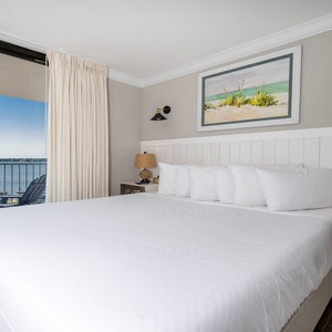 Master bedroom featuring a plush king bed and stunning views of the water through large sliding glass doors