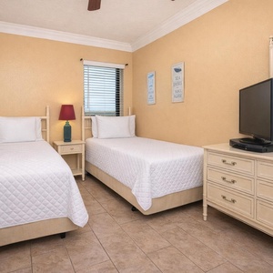 This guest bedroom features two twin beds, a TV, and charming decor, perfect for a relaxing getaway