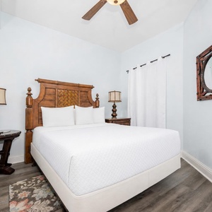 This guest bedroom features a stylish wooden bed frame, soft white linens, and elegant decor, creating a serene retreat
