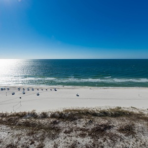 Gaze at the shimmering water and beach from your balcony, where relaxation meets stunning coastal views