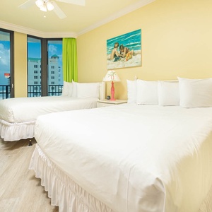 Unwind in this guest bedroom featuring two comfortable queen beds, vibrant decor, and balcony access