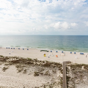 Enjoy stunning beachfront views with blue umbrellas dotting the sandy shore, perfect for a relaxing getaway