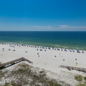 Experience breathtaking views of the beach with vibrant blue umbrellas dotting the sandy shore from your private balcony