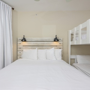 Cozy guest room featuring a queen bed with plush pillows and a twin bunk bed, perfect for family stays