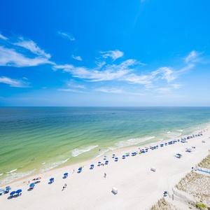 Pristine beach lined with colorful umbrellas under a clear blue sky, perfect for a relaxing getaway