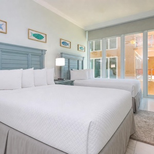 Ease into the cozy queen beds beneath coastal fish art and enjoy stunning beach views