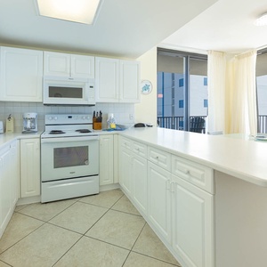 Bright white cabinetry and a spacious countertop create an inviting atmosphere in this kitchen with a view of the beach