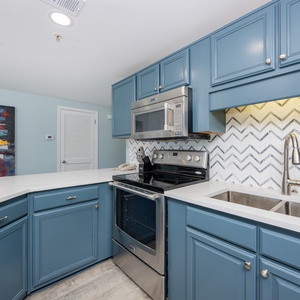 Blue cabinetry surrounds the modern kitchen where you prepare fresh meals and savor relaxed vacation vibes