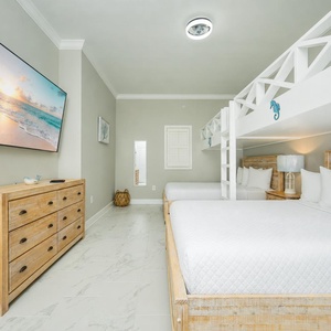 Relax in this guest bedroom featuring two queen beds, cozy twin bunks, and a large TV