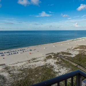 Gaze at the tranquil waters and beach from your balcony, where colorful umbrellas dot the shore for your enjoyment