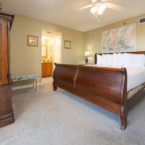 The inviting master bedroom features a wooden sleigh king bed, soft carpeting, and warm tones, creating a relaxing atmosphere