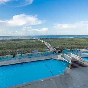 Inviting pool area with a kiddie pool, lounge chairs, and a scenic path leading to the beach, perfect for relaxation and fun