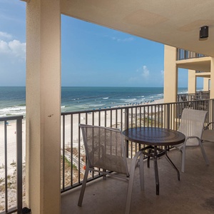 Relax on the balcony with a table and chairs, enjoying direct views of the beach and gentle waves lapping at the shore