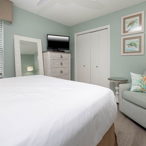 Inviting guest bedroom featuring a queen bed, a TV, and a cozy reading chair for your leisure