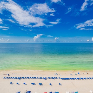 Enjoy the vibrant beach scene with colorful umbrellas and sunbathers, inviting you to relax by the water's edge