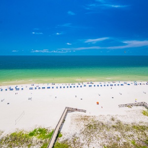 Breathtaking view of a pristine beach with vibrant blue umbrellas and soft white sand under a clear blue sky