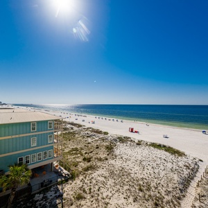 This bright view showcases the stunning beachfront with white sand and colorful umbrellas, perfect for a relaxing getaway