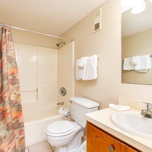 This bathroom features a clean design with a shower-tub combo, a spacious vanity, and fresh towels for your convenience