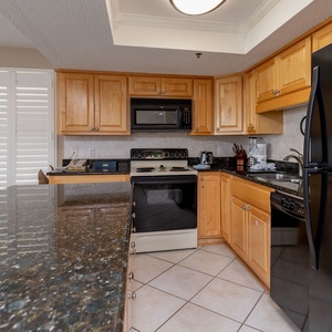 Kitchen featuring sleek black appliances, granite countertops, and inviting wood cabinetry for a cozy experience