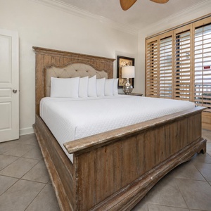 Master bedroom featuring a king bed with plush bedding, stylish wooden furnishings, and natural light from the window