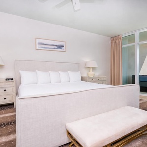This master bedroom features a king bed, elegant decor, and a stunning beachfront view from the large windows
